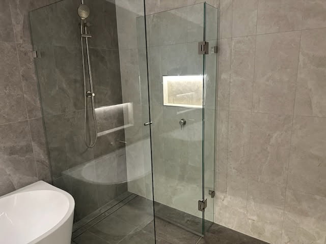 Bathroom renovation featuring Sleek Wall Hung CARMEN VANITY from Builders Discount Warehouse, complemented by ambient LED lighting underneath and elegant LED-lit niches in the shower.
